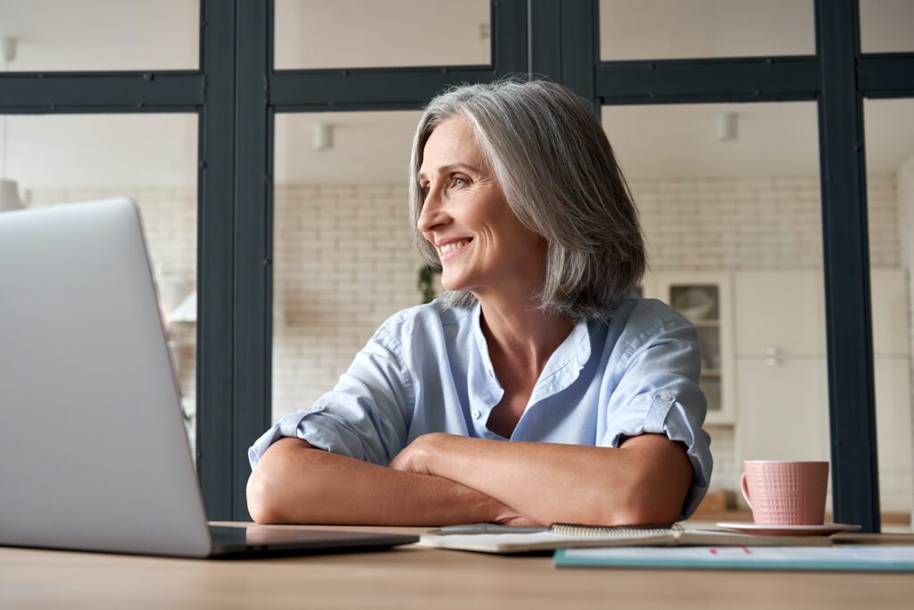 A woman smiles as she sits at her desk, more at ease because she knows the competitive advantages she has just unlocked by leveraging a managed services provider for her technology organization.