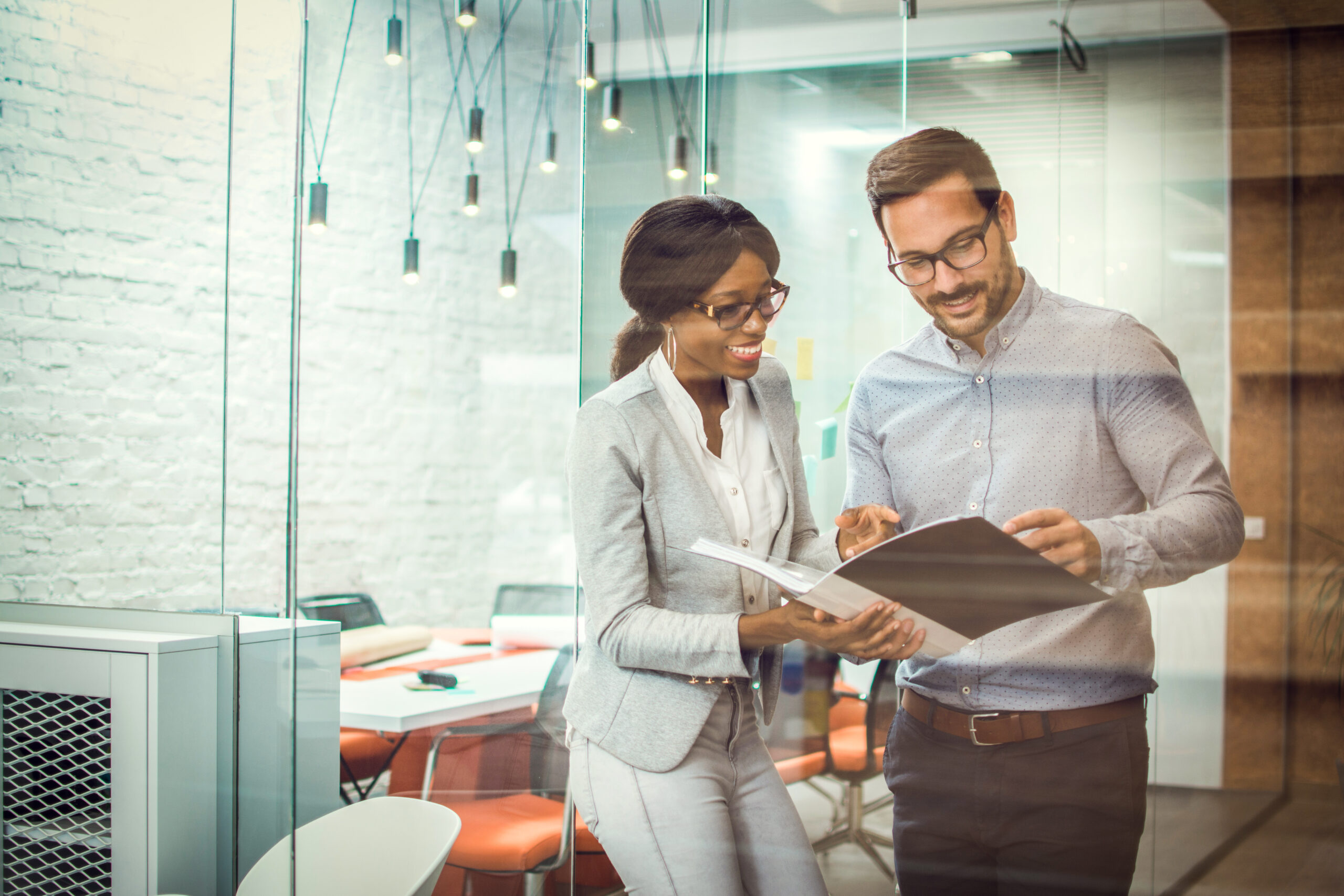2 professionals chat in an office, going over new hire paper work. Microsoft Dynamics 365 for HR