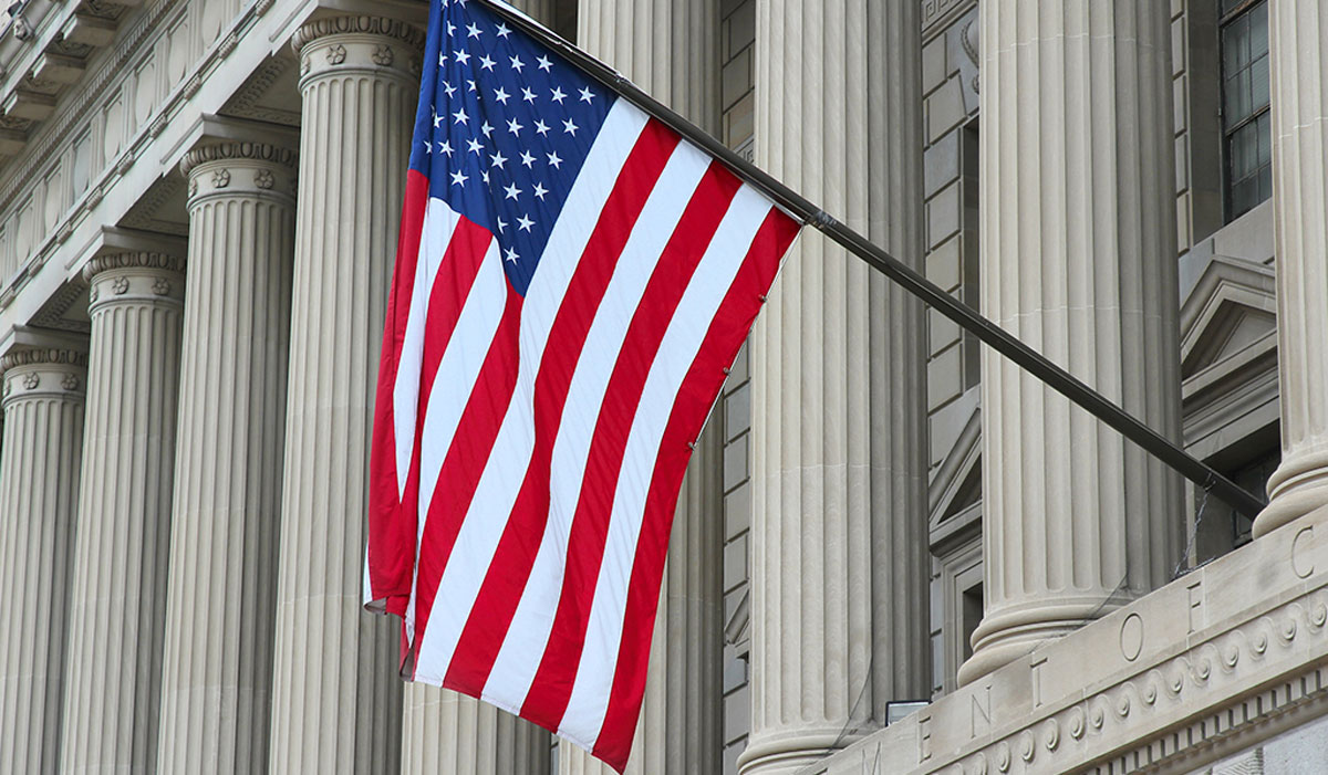 An American Flag hangs outside of an official government building. Quisitive Cloud Solutions for Public Sector State and Local Government