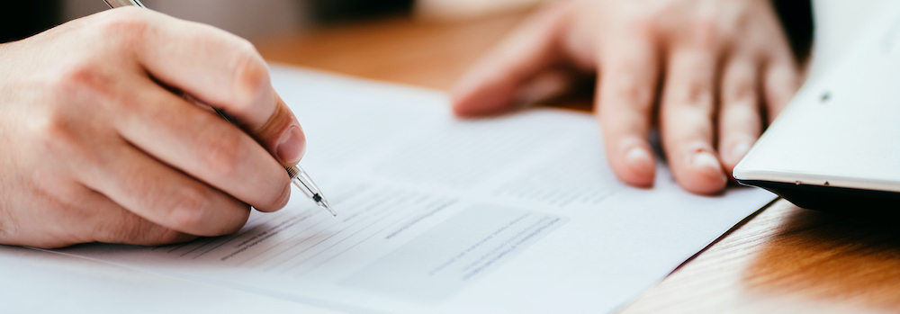 A business professional signs the documentation for his organization's software licensing agreement