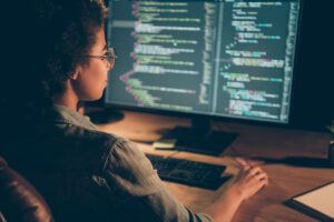 A young man works at his desk, making sure the coding for his clients Azure Data Platform is looking set up for their needs