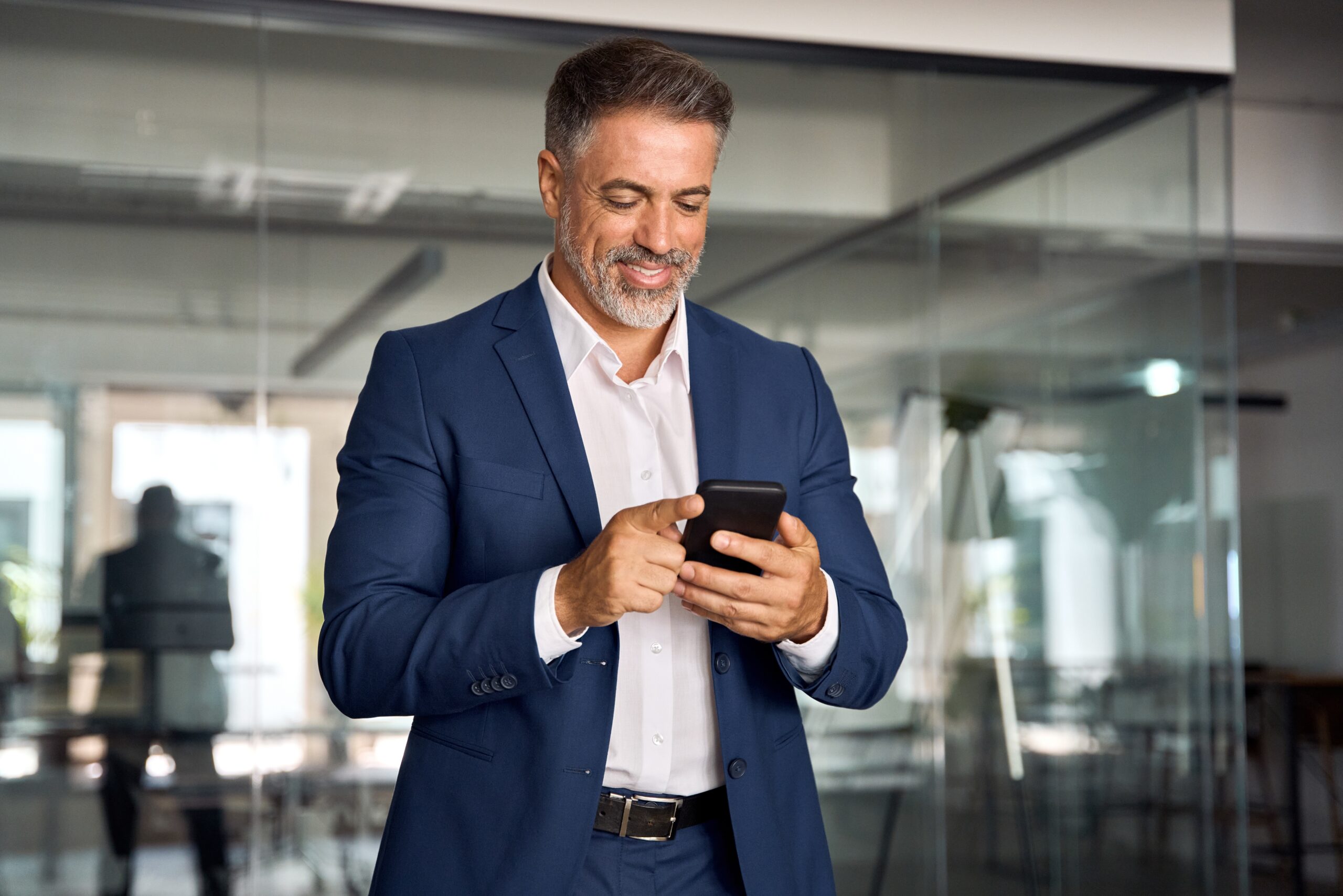 Smiling, Mature, Businessman, Holding a Smartphone In Office.