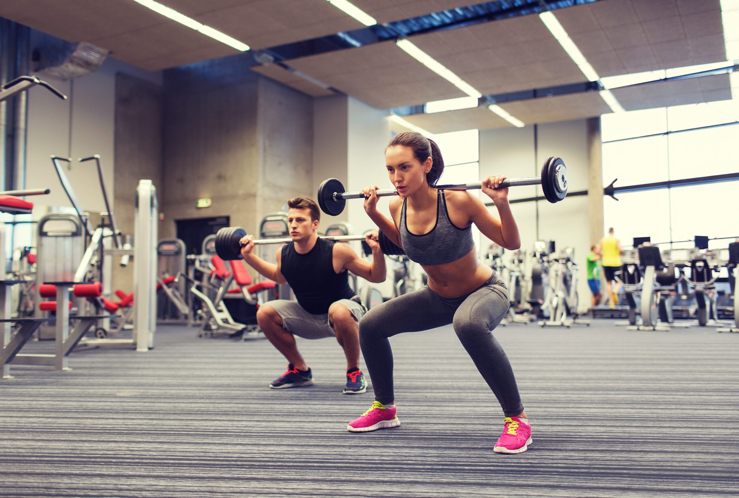 Cambridge group of clubs cloud ERP solution case study feature image: a man and woman do squats with weights in a gym