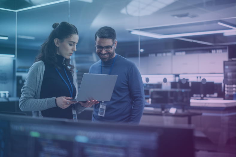 Blog Feature Image - Ai Governance Framework, What it is and Why it matters - 2 engineers stand in an office looking at a laptop