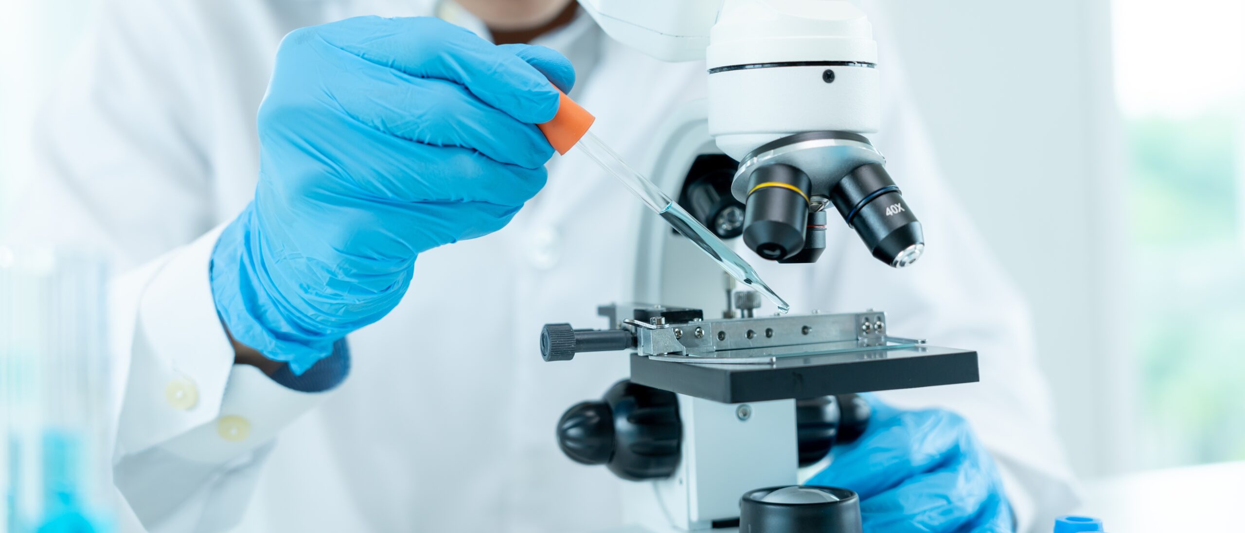 PTC Dynamics 365 Case Study Hero Image: a scientist in a lab analyzes a sample under a microscope