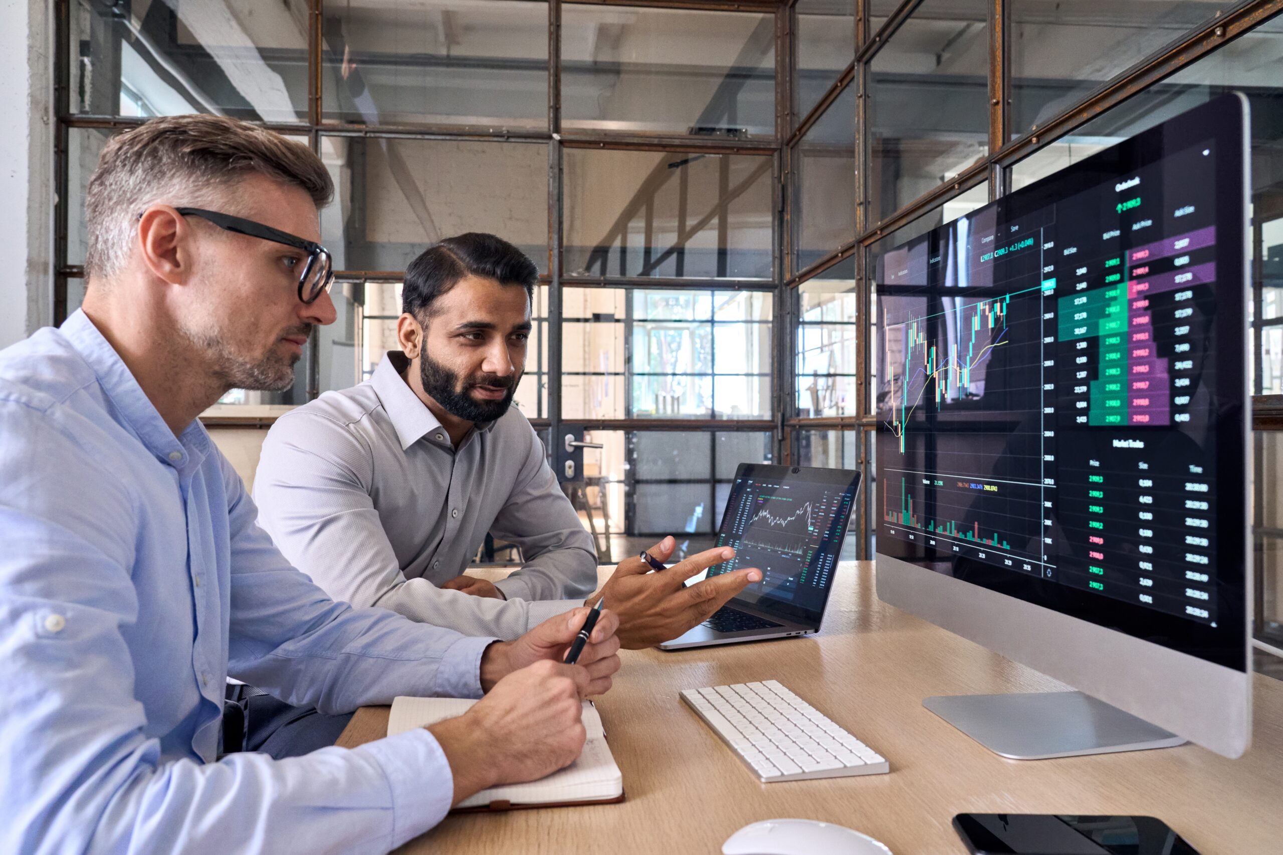 Azure Cost Optimization Best Practices - 2 professional men look at financial reports on a computer