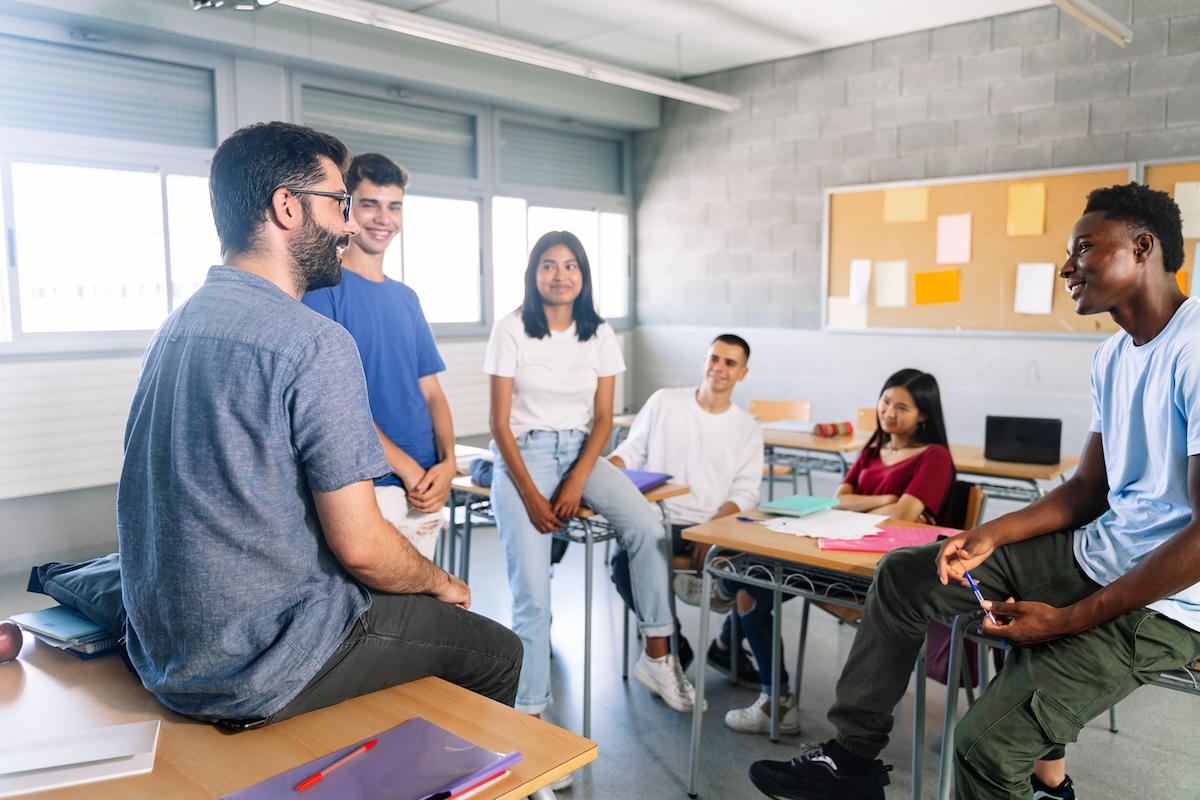 Case Study Lakeside Programs - Teenager students listening and talking with friendly young male teacher - Group discussion