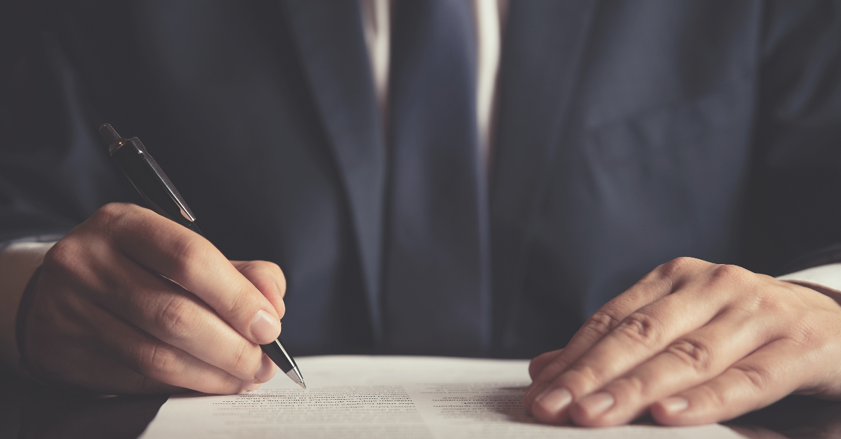 A man signs a paper contract at a desk - case study feature image for technology consulting firm AI-Powered M&A contract analysis and insights